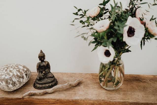 Praxisambiente mit Stein, Buddha, Holz und Blume